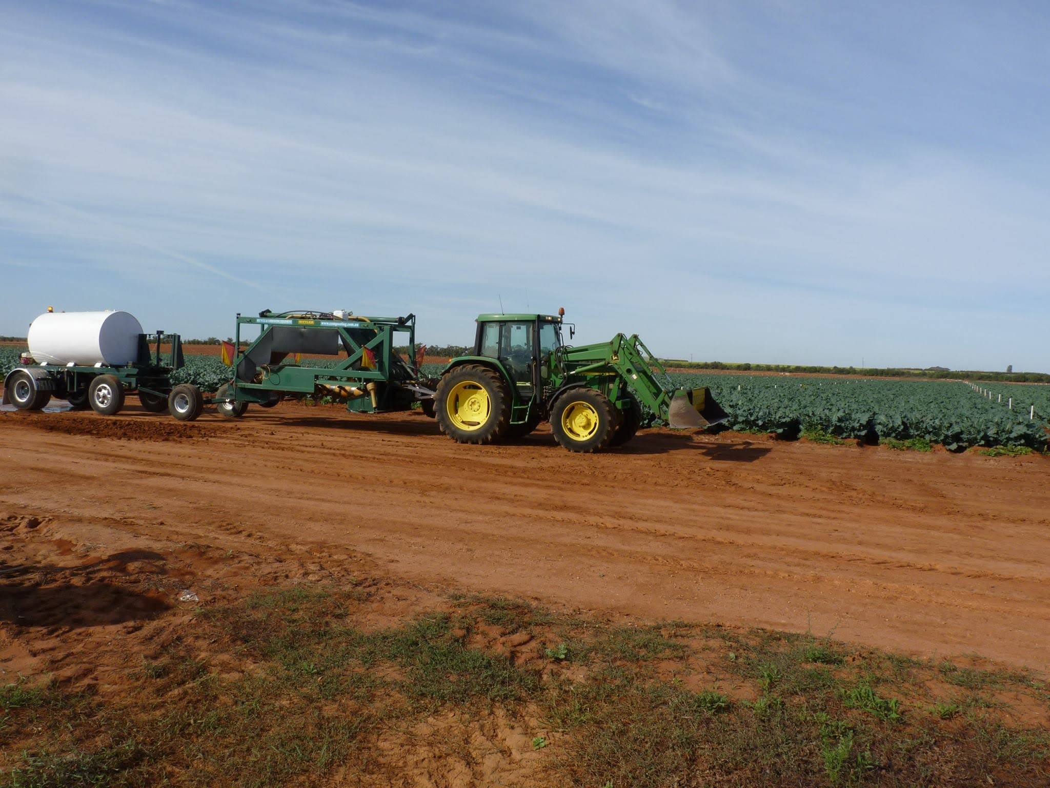 Tractor and equipment alongside commercial crop rows